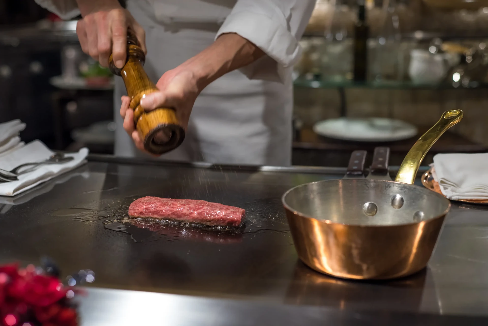Koch würzt ein Steak auf dem Grill im Roomsteak Grillhouse